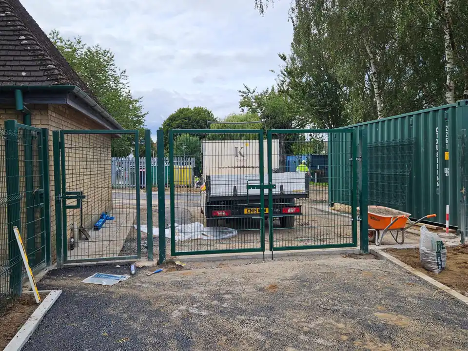 Green mesh double gates to a utility compound with a Kingsley truck behind