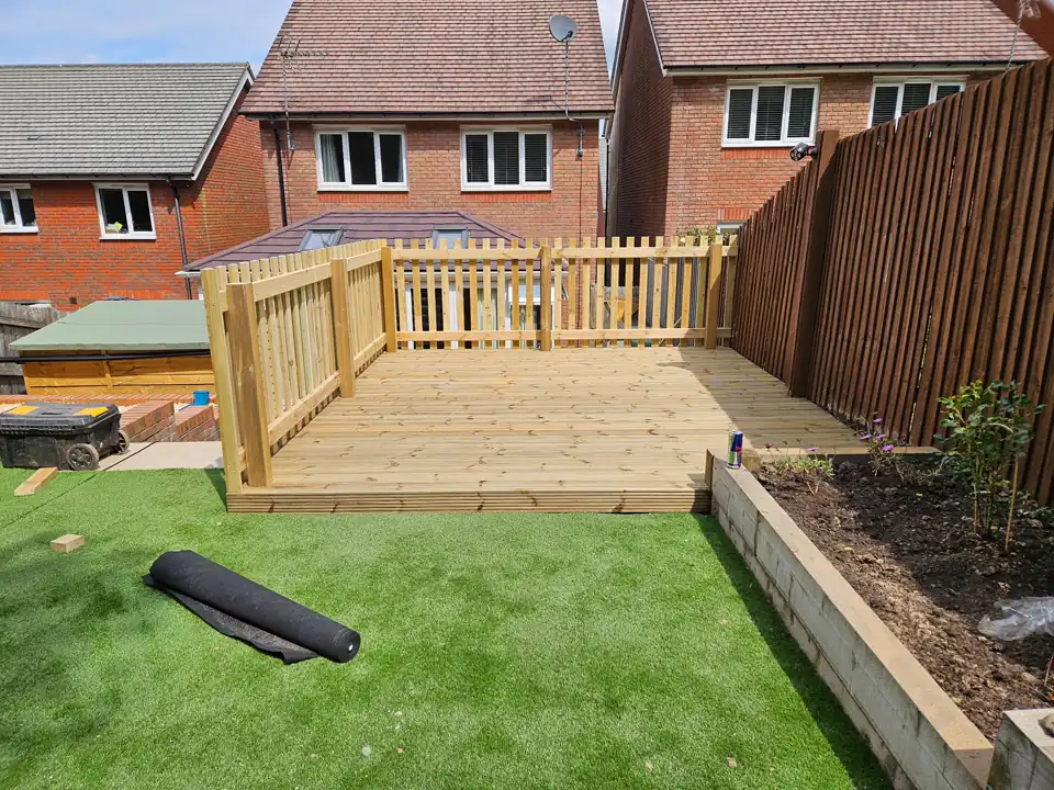 Raised timber deck with picket balustrade beside new artificial turf