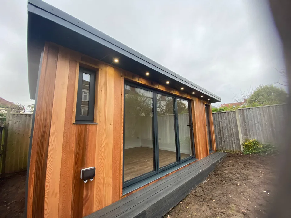 Timber-clad garden room with bi-fold doors and soffit lighting