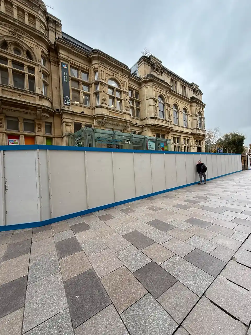 Painted hoarding run with blue trim along the Old Library frontage, the Hayes, Cardiff