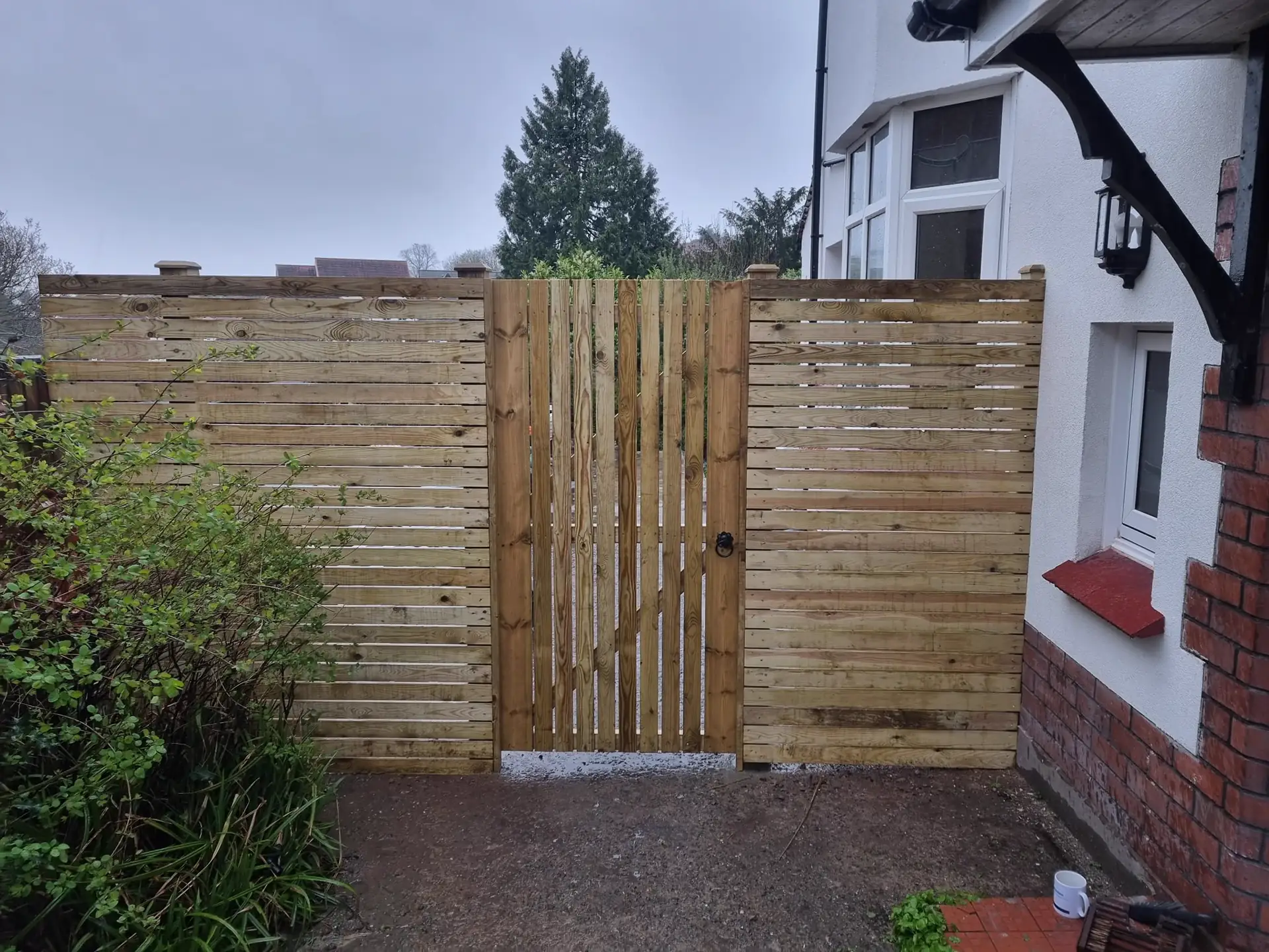 Horizontal slatted fence with matching gate beside a house, by Kingsley Build Group