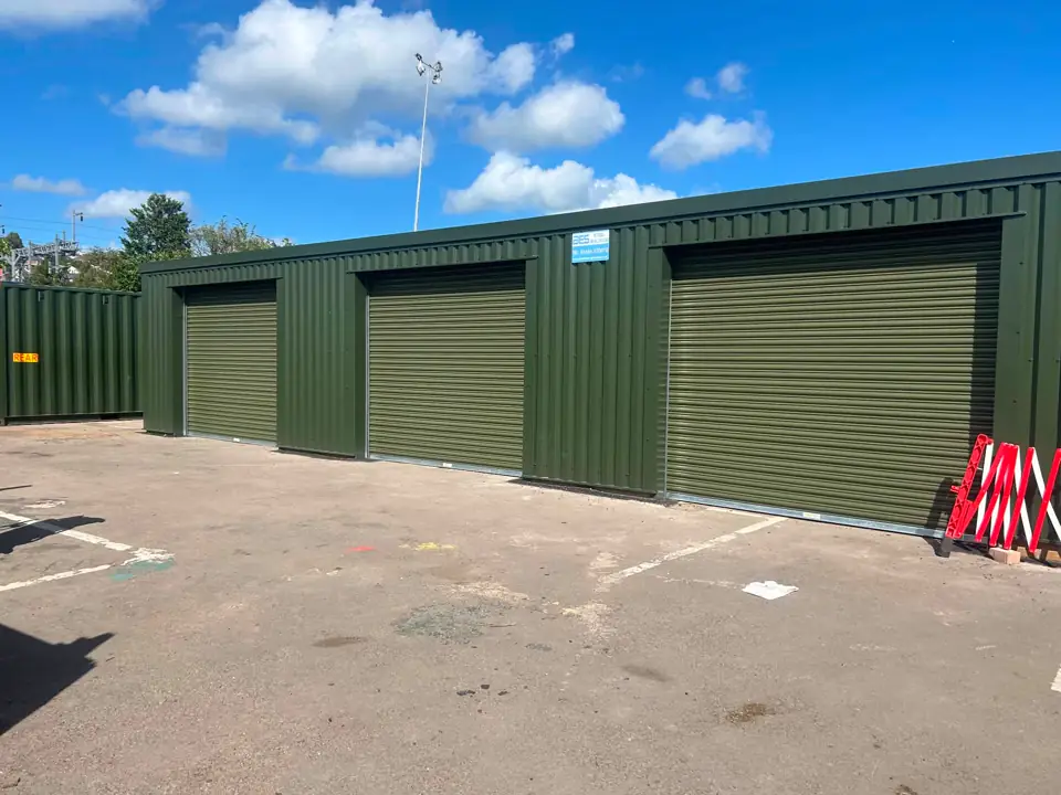 Green steel-clad garage bays with roller-shutter doors at a council depot