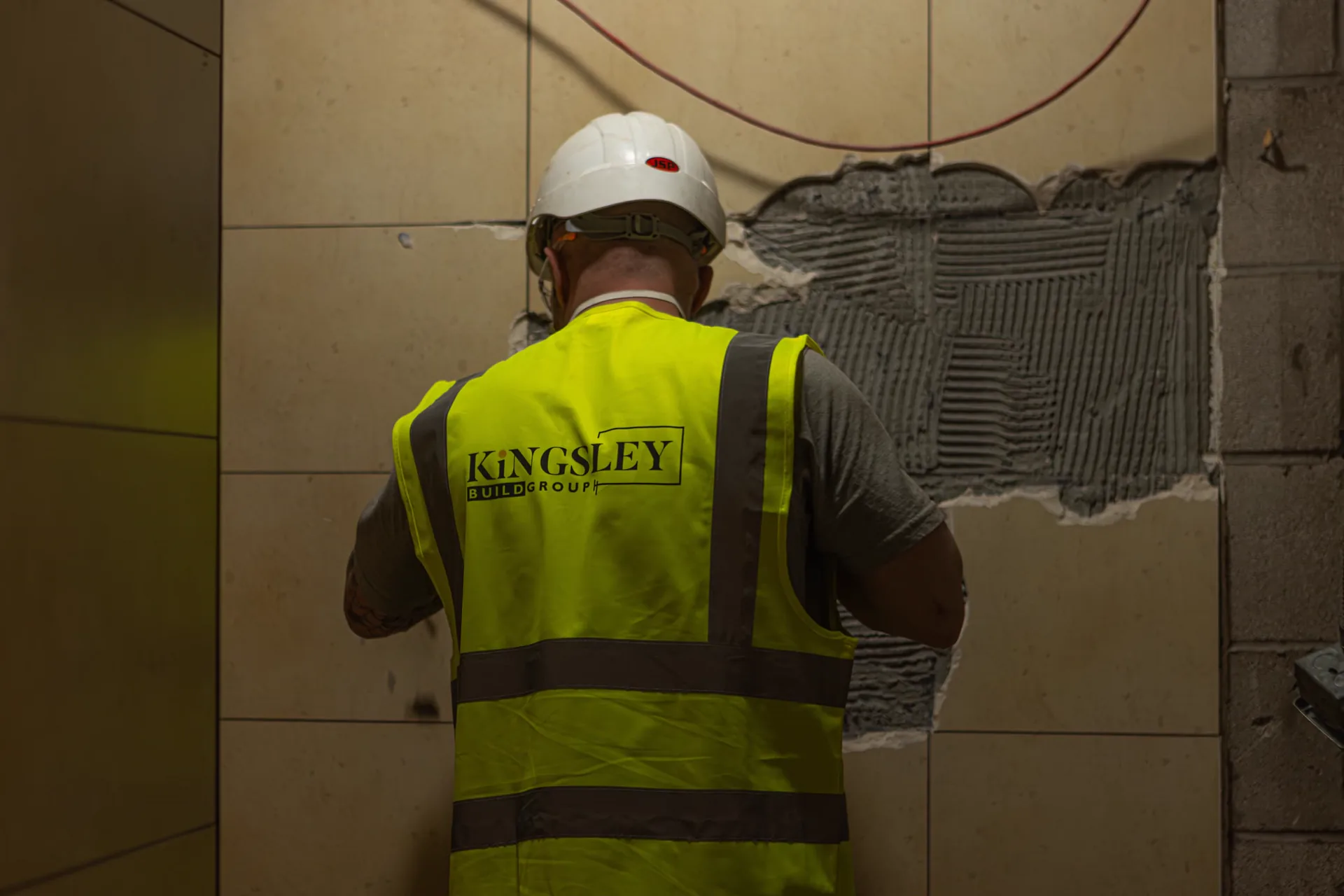 Kingsley Build Group operative re-tiling an interior wall on a refurbishment