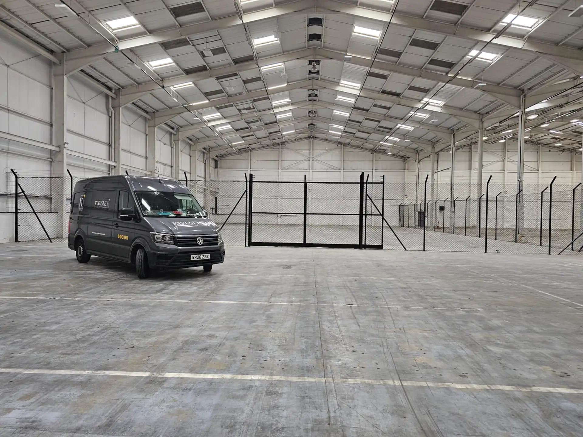 Welded-mesh security partitioning and gates inside a Newport warehouse, Kingsley van alongside